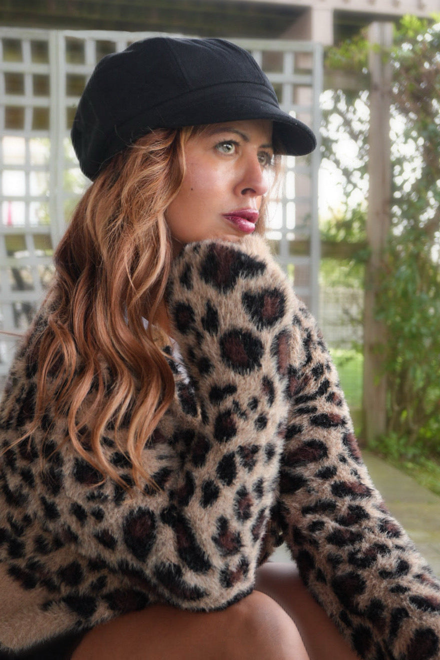 Woman wearing a black cap and leopard print sweater outdoors