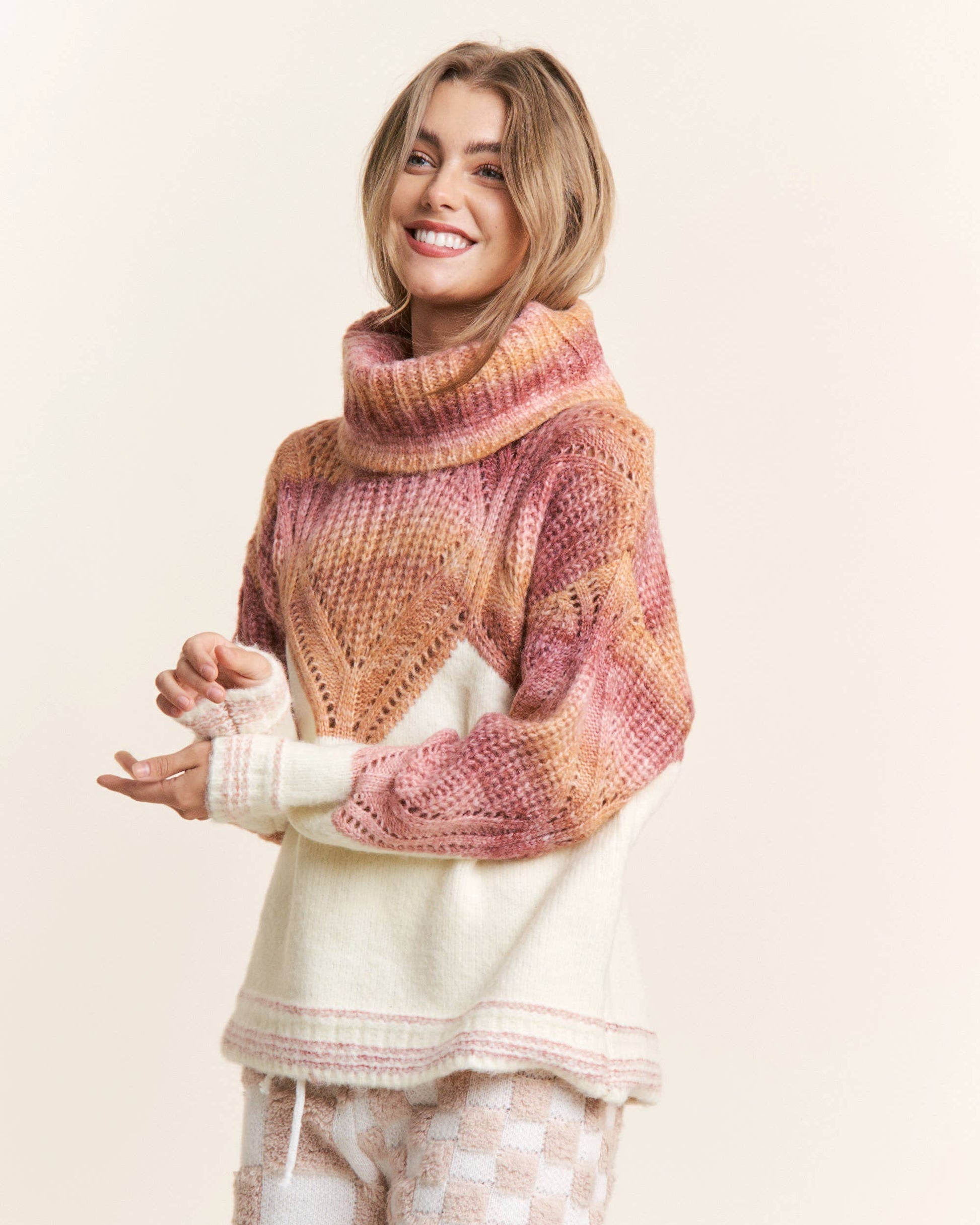 A woman wearing an orange and pink ombre cowl neck sweater with a chevron pattern.
