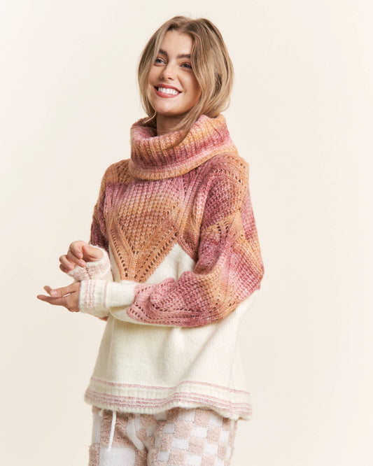 A woman wearing an orange and pink ombre cowl neck sweater with a chevron pattern.